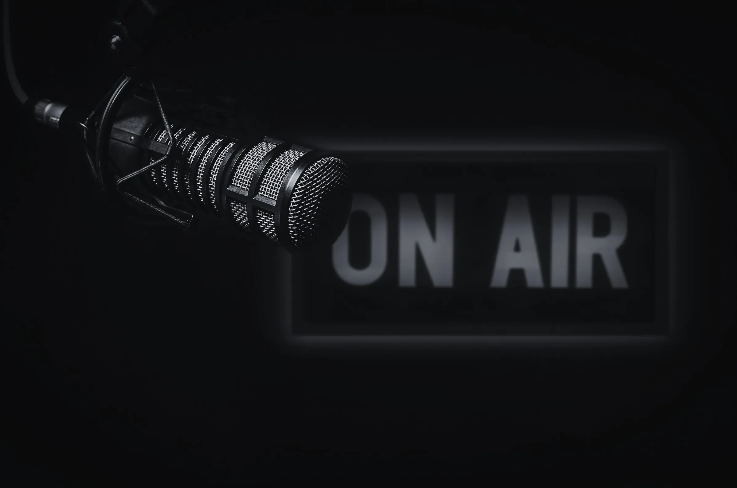Radio studio microphone beneath a glowing ON AIR sign